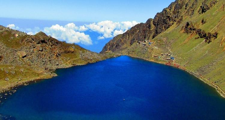 Lac bleu profond entouré de collines rocheuses et de végétation clairsemée.