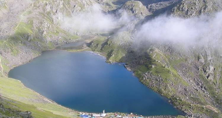 Lac de montagne avec des nuages brumeux et des vallées vertes.