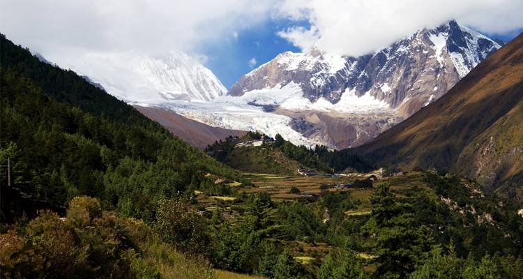 Forested valley with towering snow-covered peaks.