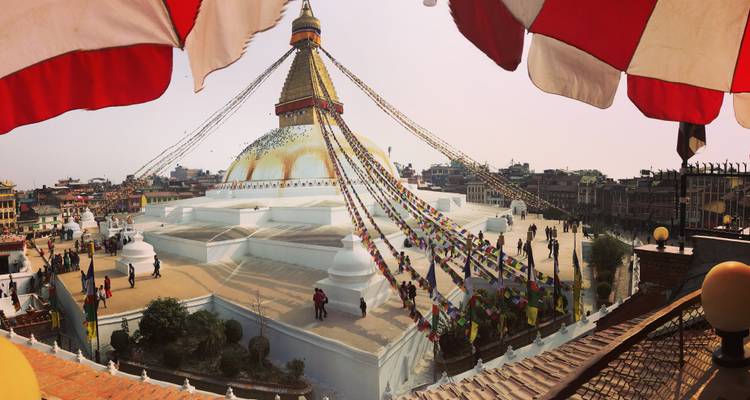 View of Boudhanath Stupa with prayer flags and surrounding city.
