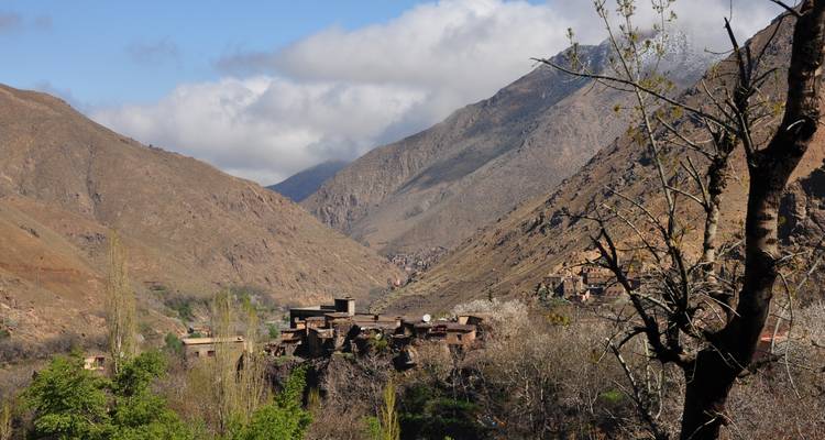 Vista de valle montañoso que muestra un pequeño pueblo en la ladera con árboles.