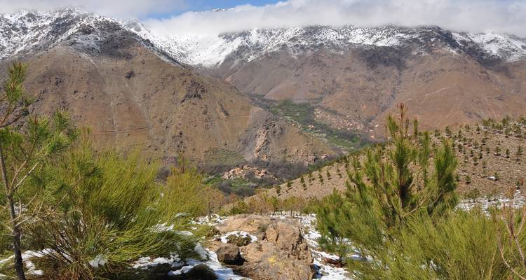 Vista panorámica de montañas cubiertas de nieve con un pequeño pueblo enclavado entre ellas.