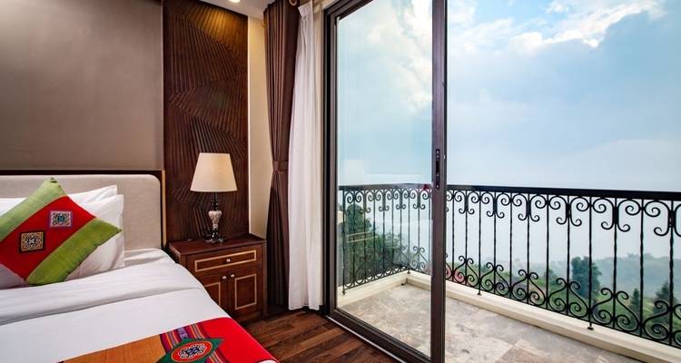 Chambre d'hôtel avec balcon vue sur la montagne accessible par une porte-fenêtre coulissante.
