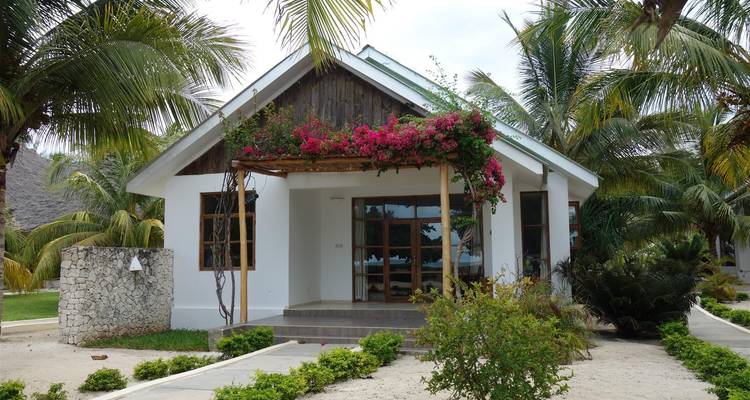 Cottage umgeben von tropischen Pflanzen und Palmen.