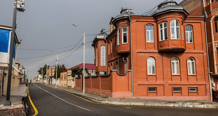Vue de rue avec des bâtiments en briques rouges et des lignes électriques.