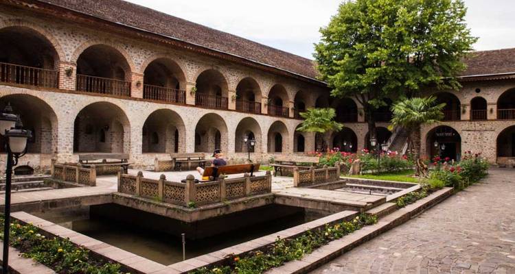 Cour historique avec arches en pierre et passage couvert.