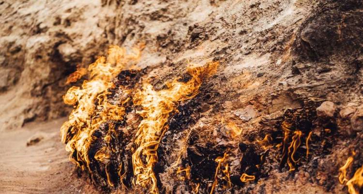 Flammes de gaz naturel brûlant sur un paysage rocheux.