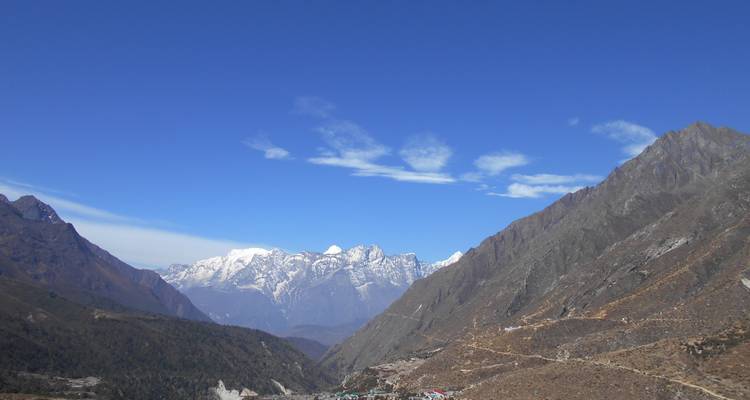Vallei met besneeuwde bergen in de verte onder een blauwe hemel.