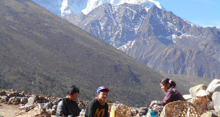 Mensen die zitten met manden en bergen op de achtergrond.