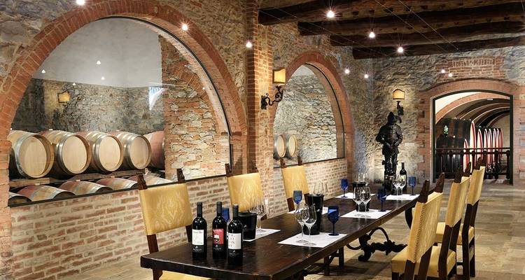 Cave à vin avec des tonneaux en bois et une table de dégustation.