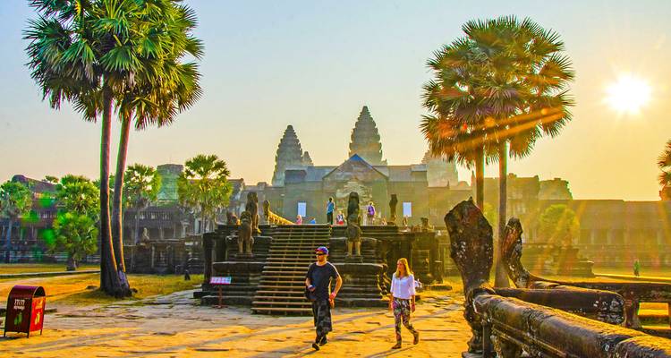Toeristen die wandelen in de binnenplaats van Angkor Wat omringd door palmbomen.