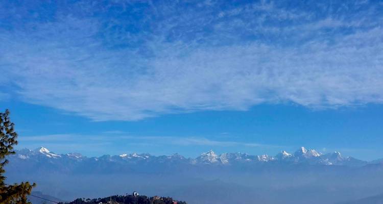 Bergketen met besneeuwde toppen onder blauwe luchten.