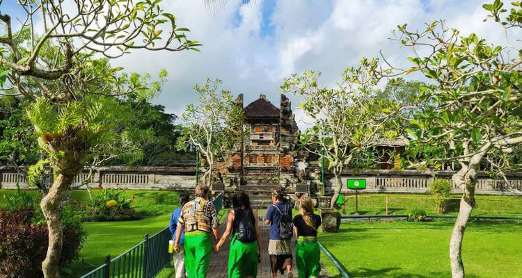 Turistas caminando hacia un templo ornamentado en jardines frondosos.