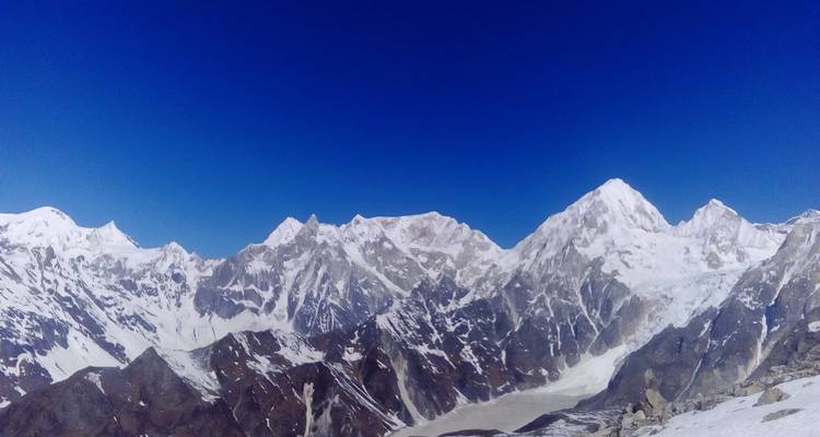 Besneeuwde bergketen onder een strakblauwe hemel.