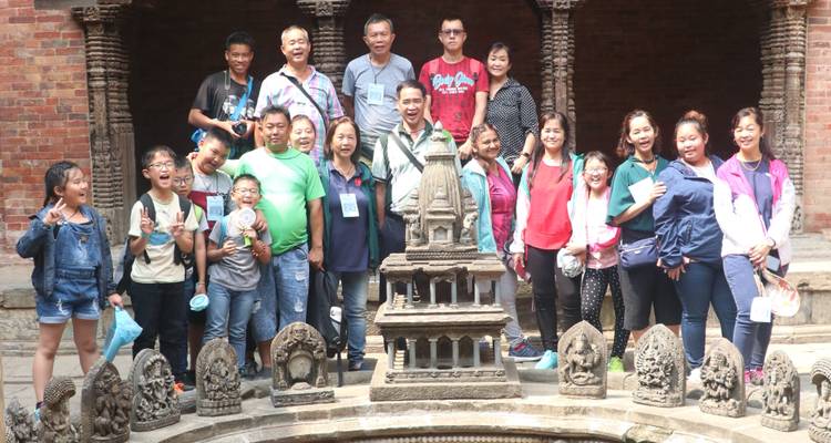 Group of tourists posing in front of a traditional stone structure.