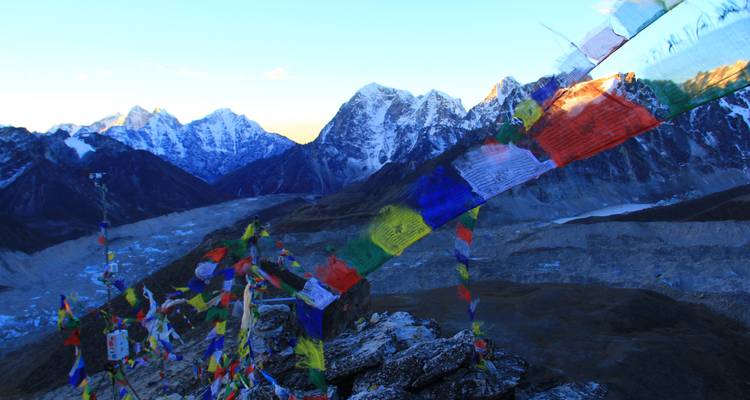 Bunte Gebetsfahnen mit majestätischer Gebirgskette im Hintergrund.