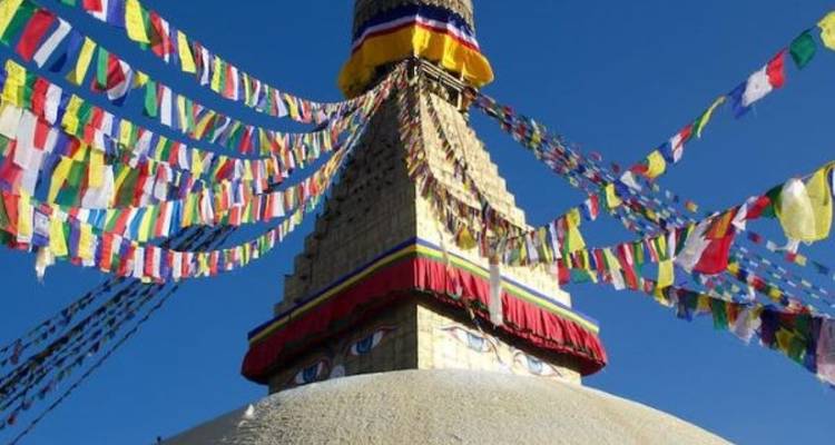 Colorful prayer flags draped over a large stupa.