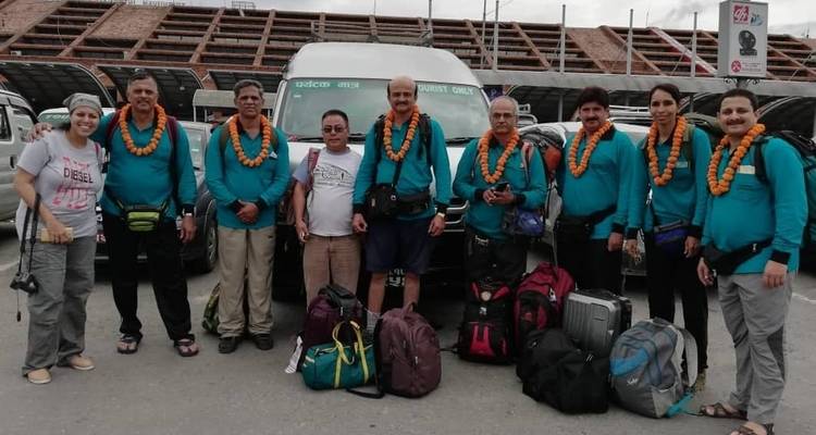 Group of travelers with garlands in front of a bus.