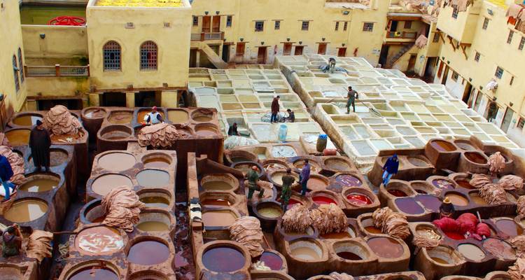 Arbeiders in een traditionele leerlooierij met kleurrijke verfputten.