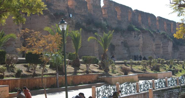 Historische muren met mensen die ernaast zitten en wandelen.