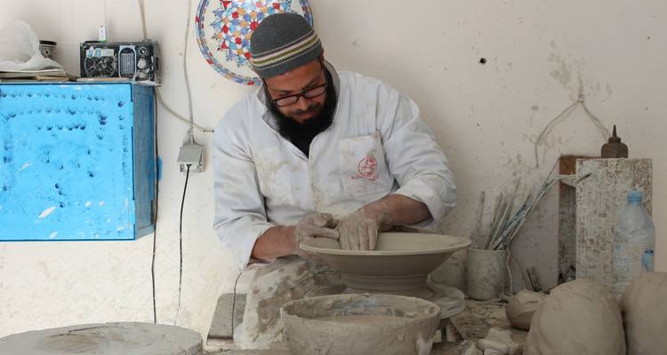 Een ambachtsman die klei vormt op een pottenbakkersschijf.