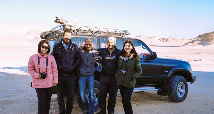 Gruppenfoto vor einem Jeep in der Wüste.
