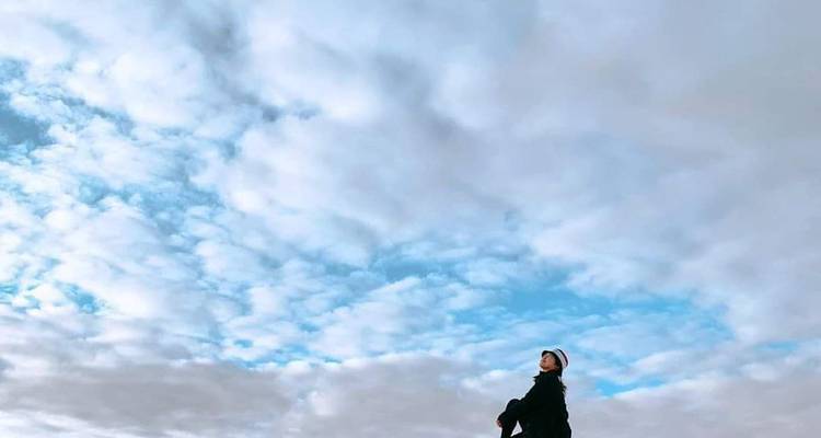 Person, die unter einem bewölkten Himmel steht.