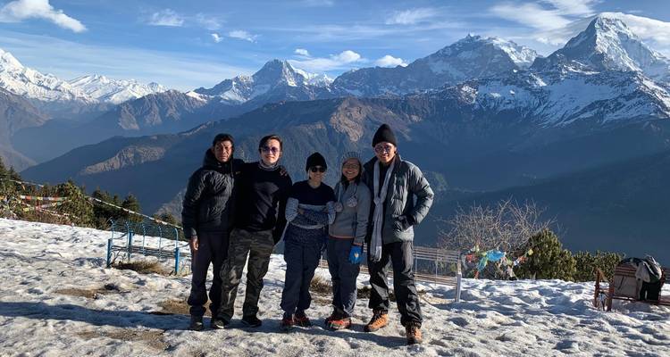 Groupe de personnes posant avec des montagnes enneigées.