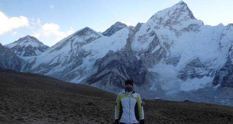 Personne debout devant de hauts sommets enneigés.