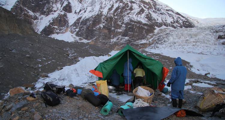 Een kampeeropstelling op een rotsachtig en besneeuw berglandschap.