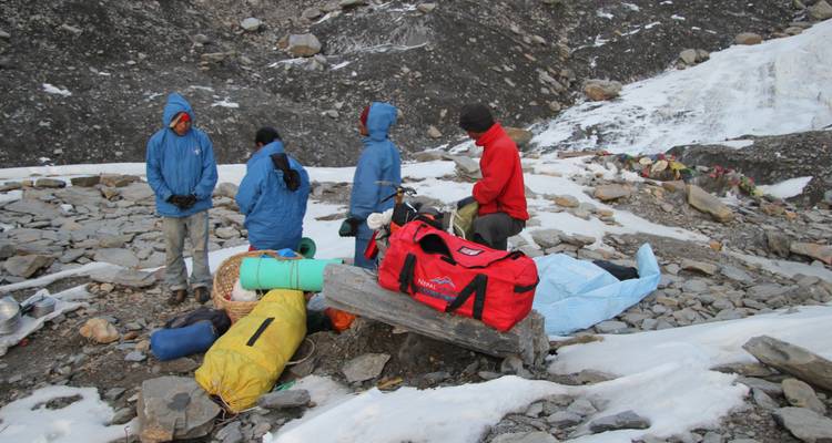 Groep wandelaars die zich voorbereiden op een tocht over rotsachtige en besneeuwde grond.