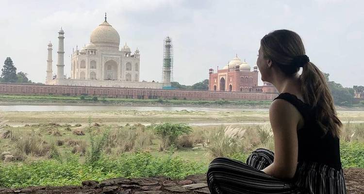 Vrouw zittend, kijkend naar de Taj Mahal vanaf de overkant van de rivier.
