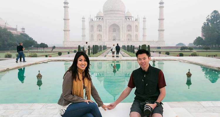 Een stel dat zit voor de reflectiepoel van de Taj Mahal met andere bezoekers op de achtergrond.