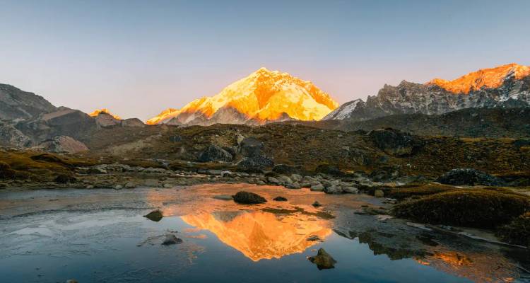 La lueur dorée de l'alpenglow sur un pic de l'Himalaya se reflétant parfaitement dans un lac alpin calme au crépuscule.