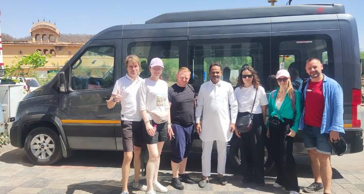 Groep mensen die voor een bestelwagen staan met Indiase architectuur op de achtergrond.