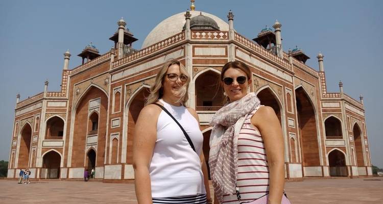 Dos mujeres posando frente a un gran edificio histórico.