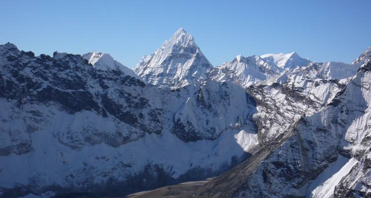 Dramatischer schneebedeckter Berggipfel vor blauem Himmel.