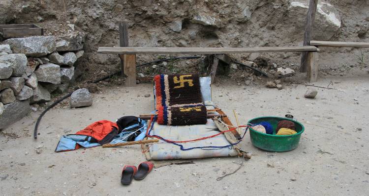 Kleurrijke weefopstelling buitenshuis op een aarden ondergrond.