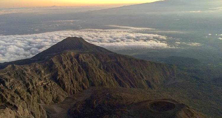 Een bergtop boven de wolken tijdens zonsondergang.