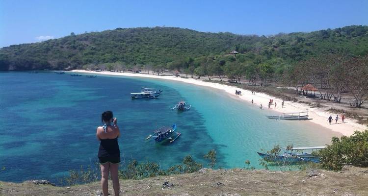 Tourist taking photograph of beach with several boats.