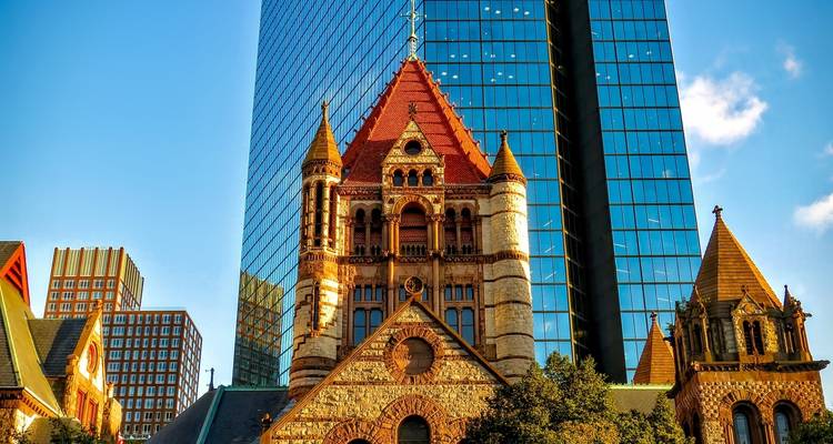 Old stone church juxtaposed with modern glass skyscraper in Boston.