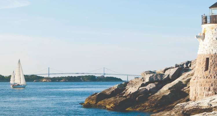 Bridge and sailboat on a rocky shoreline.