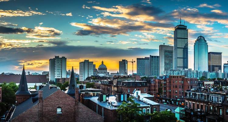 Boston skyline at sunset with iconic buildings and colorful sky.