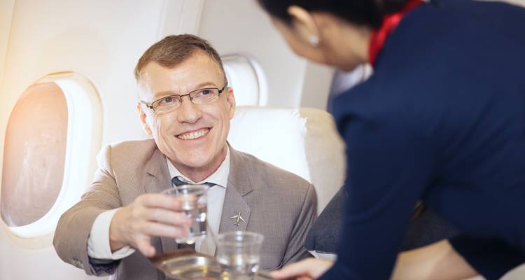Man receiving a drink from a flight attendant on a plane