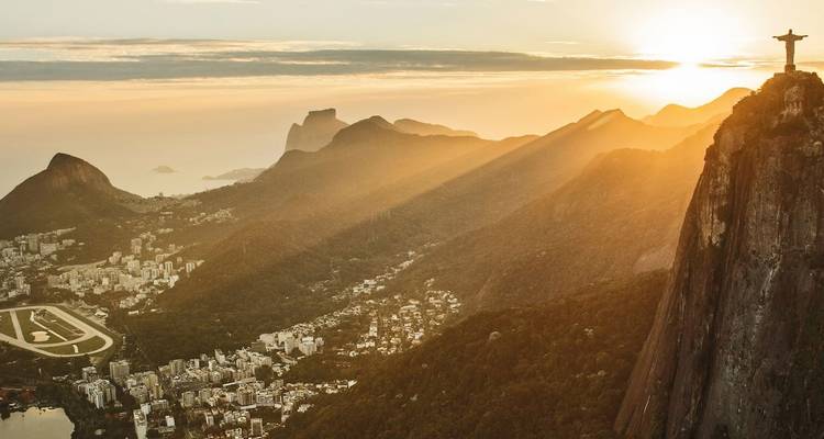 Río de Janeiro al amanecer con la estatua del Cristo Redentor iluminada por rayos dorados que dominan la ciudad y el Pan de Azúcar