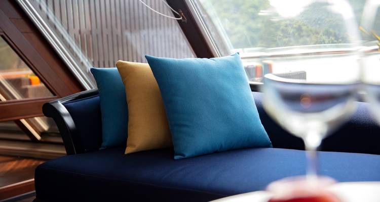 Drei bunte Kissen auf einem Sofa mit Blick nach draußen.