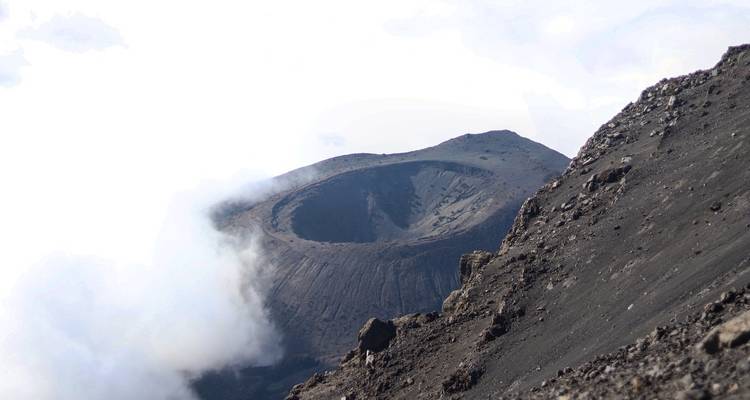 A crater at the peak of a mountain surrounded by clouds.