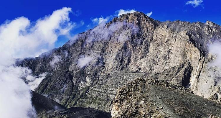 Dramatic mountain peak with clouds and blue sky.