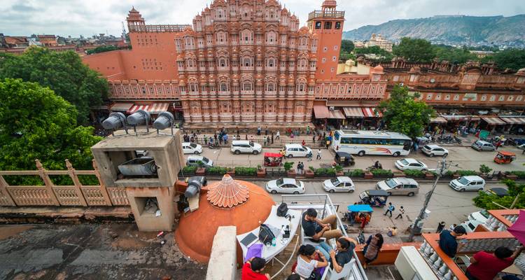 Escena callejera bulliciosa bajo la fachada rosa ornamentada del Hawa Mahal en Jaipur