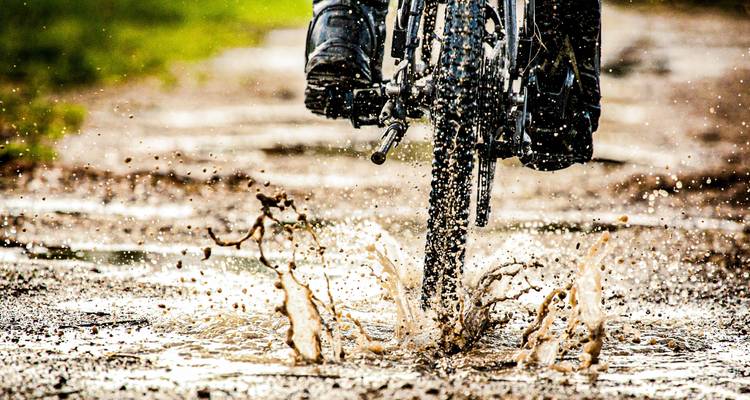 Close-up of a bicycle tire splashing through a puddle.